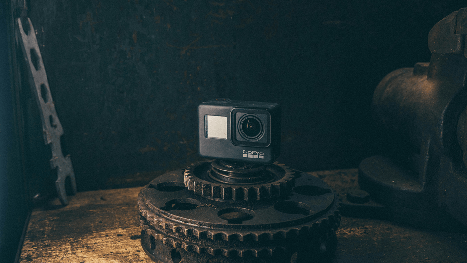  A GoPro camera sits on a gear on a table, filming content about where to find royalty free sound effects for GoPro videos.