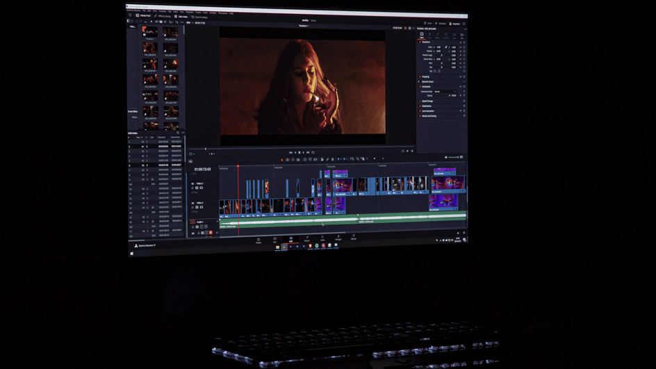  A black flat screen computer monitor displays an edit, while a content creator adds music for Davinci Resolve