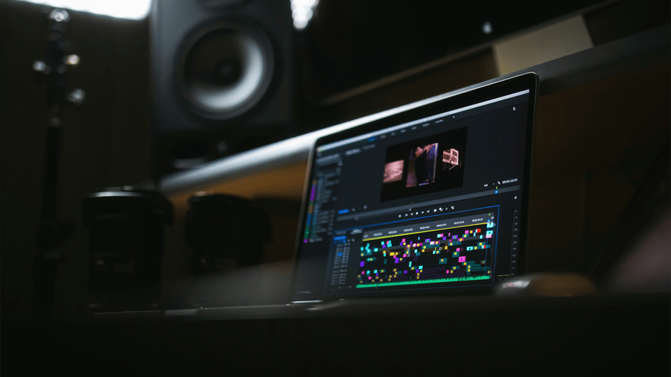  A content creator learns how to add music to Premiere Pro on their laptop on a brown wooden table.