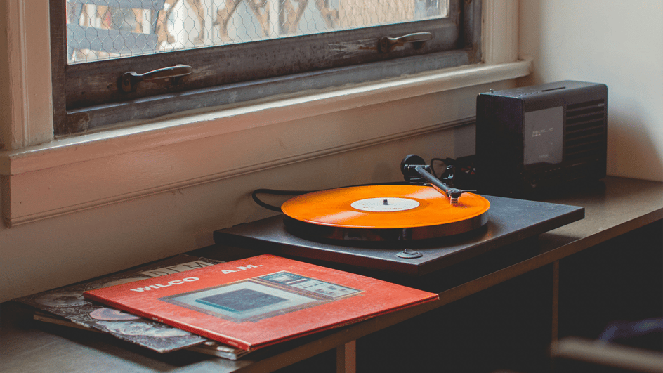  A grey turntable plays an orange record, while the listener ponders about how to use copyrighted music in Adobe Express.