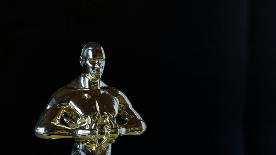  A gold Oscar statue waits to be presented to the winner of the best original score, likely a composer who also creates royalty free music for filmmakers.