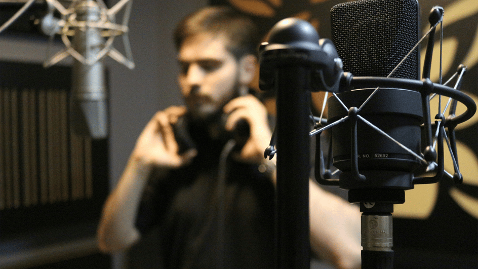  A vocalist in a recording studio puts his headphones on to record royalty free music with lyrics for video.