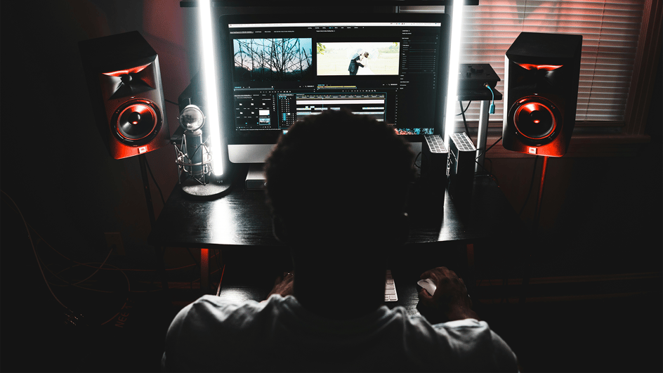  Man sitting at his video editing console, using a video and audio editor ai interface with audio editing plugins to complete his video