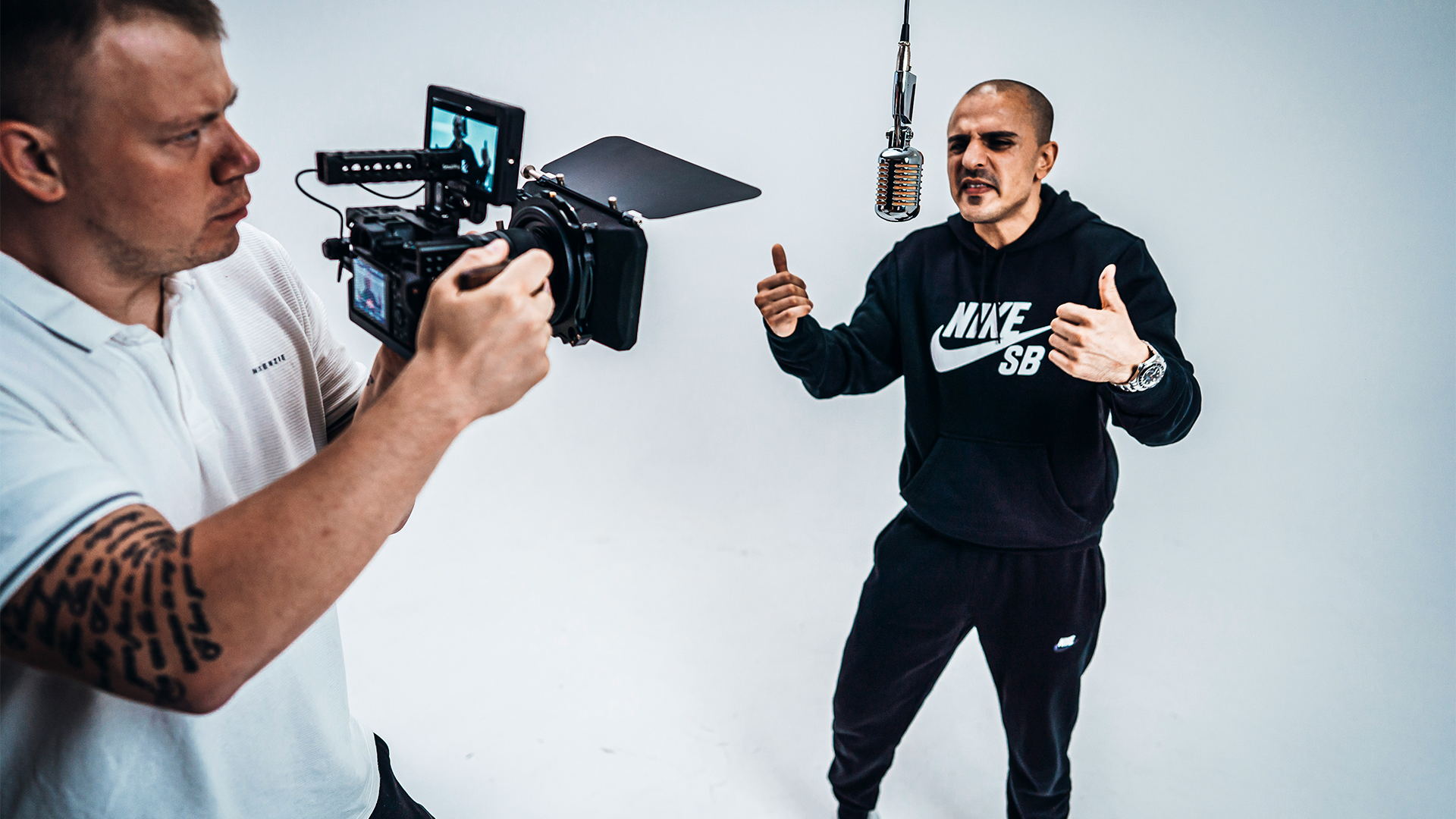A videographer captures a man singing into a microphone, wondering, “How many views to go viral?”